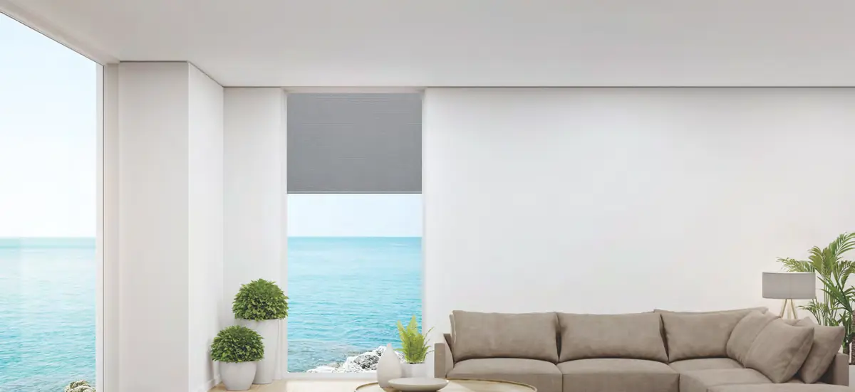 A roller blind half drawn over an ocean view