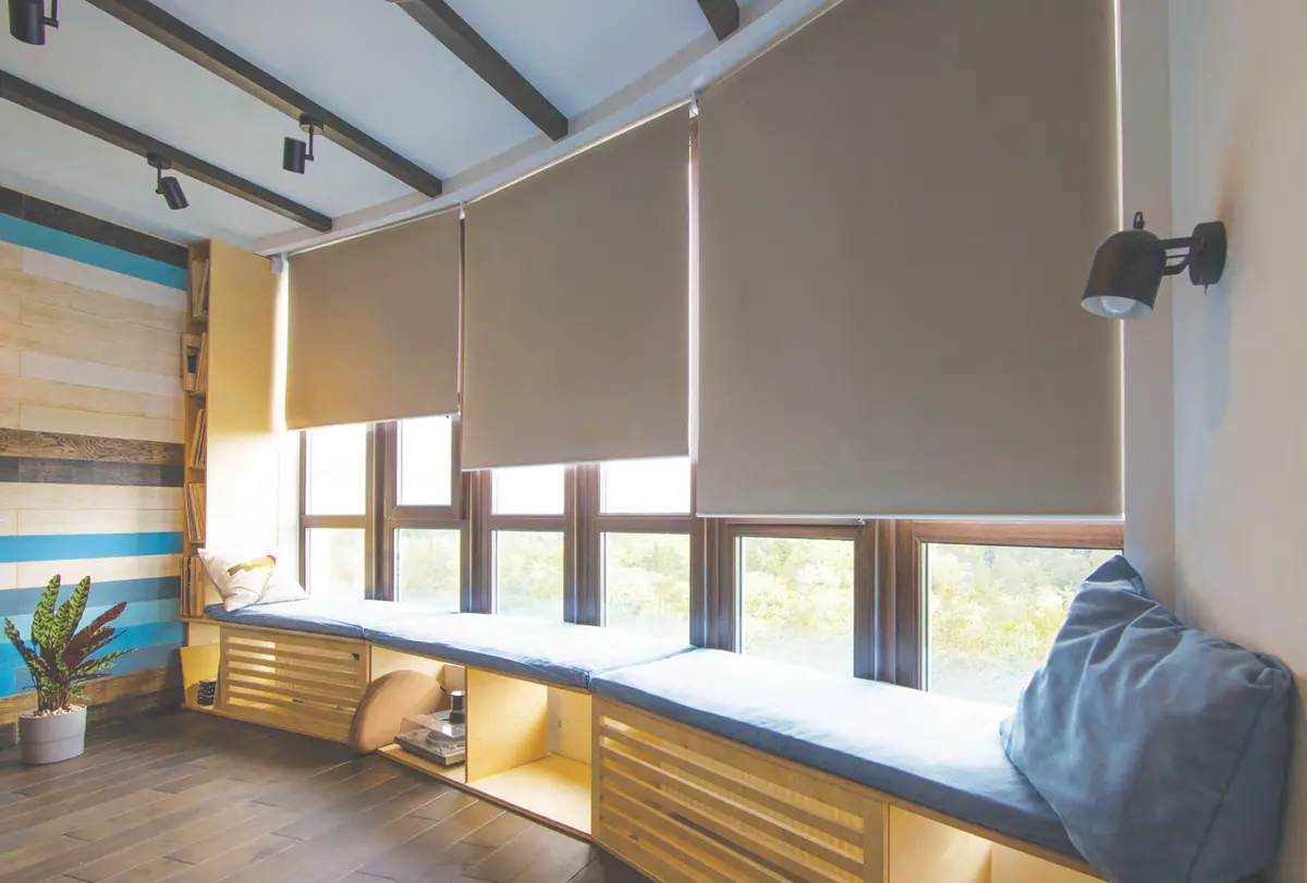 Three roller blinds at different heights above a timber window seat